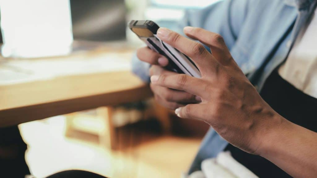 A person holds a smartphone while sitting at a desk.