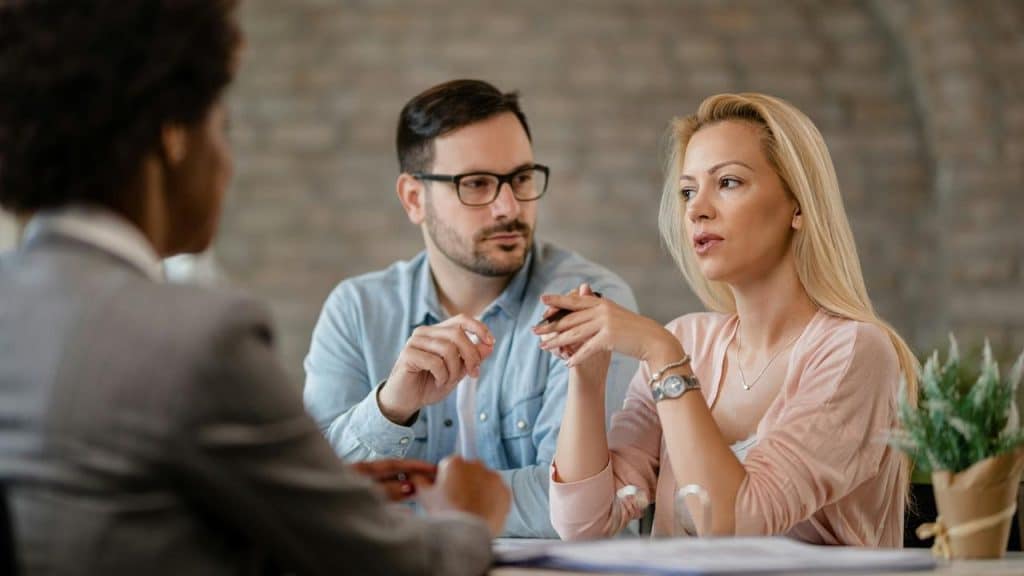 A couple talking with a professional advisor at a desk.