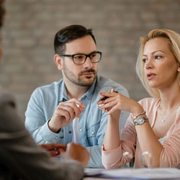 A couple talking with a professional advisor at a desk.