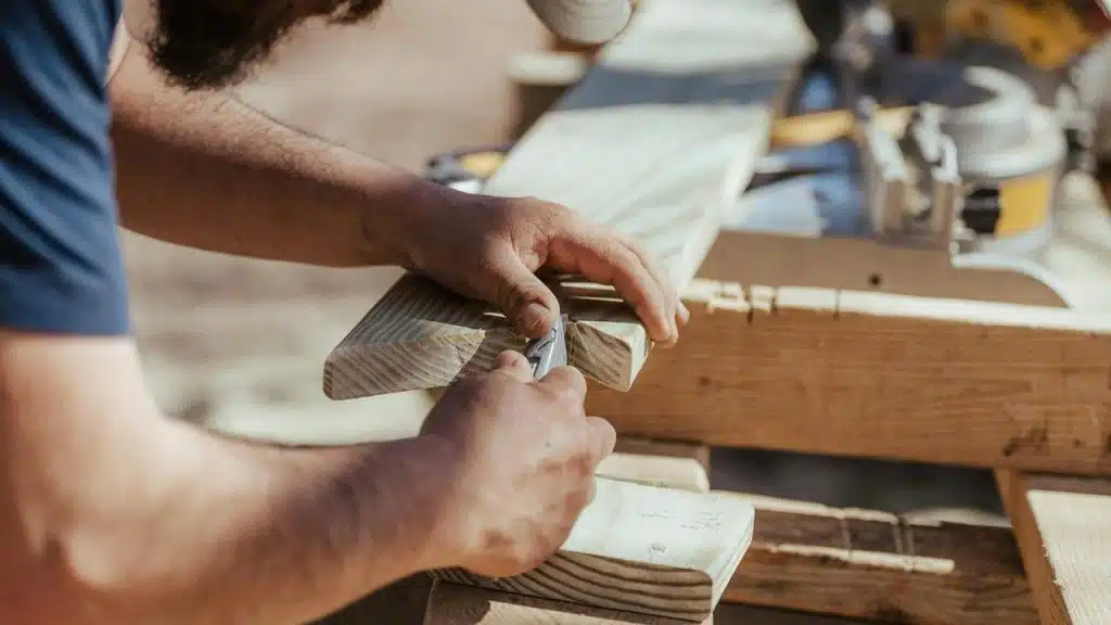 A person carving a piece of wood with a hand tool.