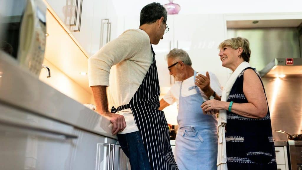 A group of three people talking and laughing together in a kitchen.