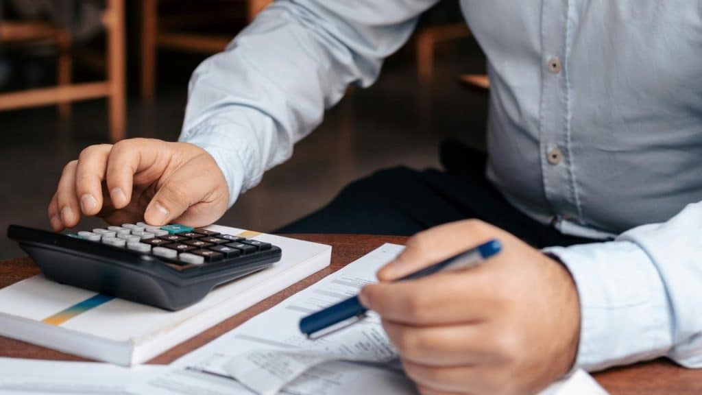 A man using a calculator while reviewing financial documents.