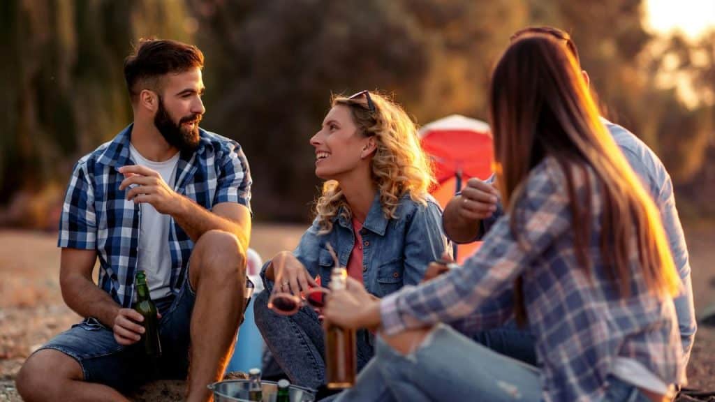 A group of friends sitting outdoors drinking and talking together.