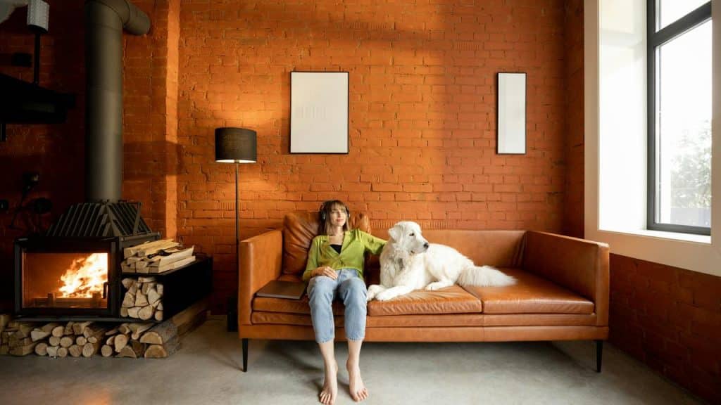 A woman relaxing on a couch with a large white dog beside her.