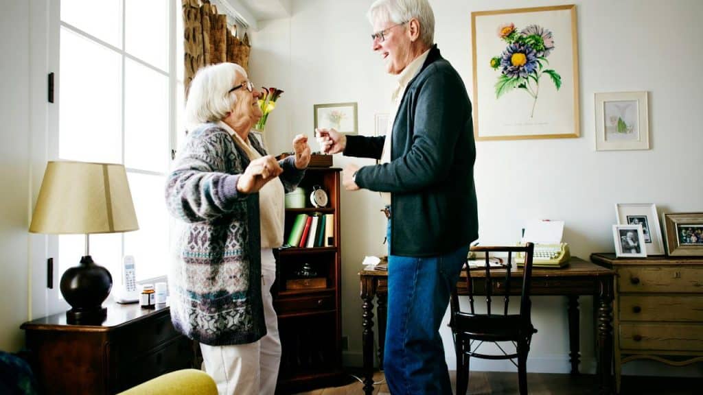 A senior couple dancing together in their living room.