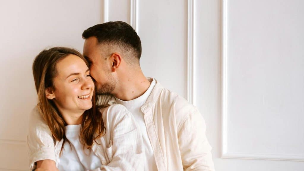 A happy couple embracing and smiling together indoors.