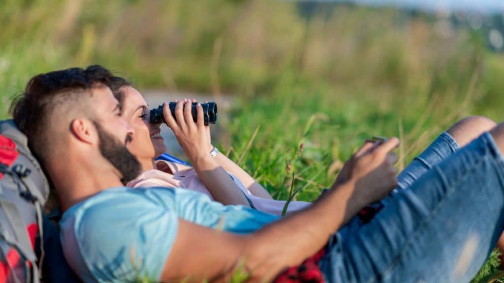 A couple lying on the grass and enjoying the view outdoors.