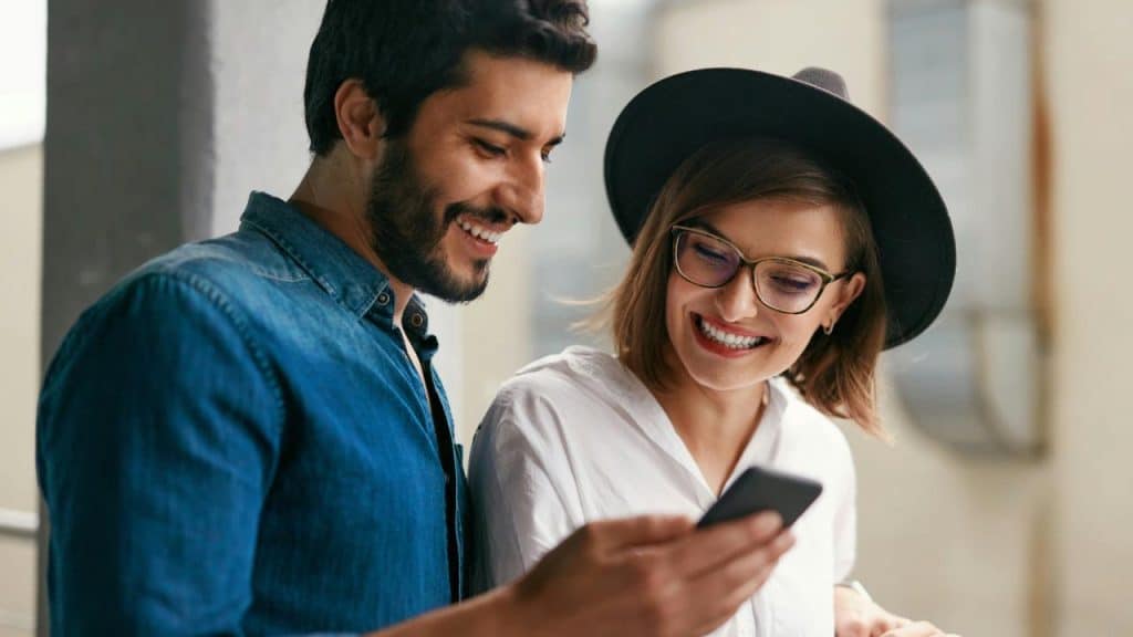 A smiling couple looking at a smartphone together.