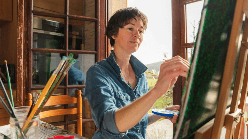 A middle-aged woman with short brown hair painting on a canvas.