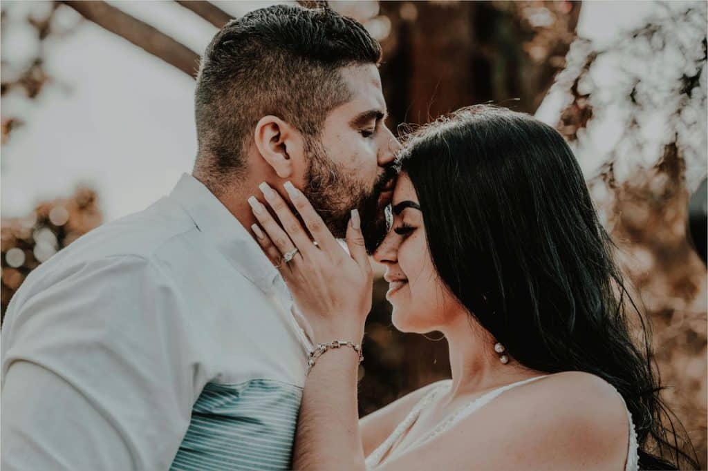 A man kissing a woman’s forehead