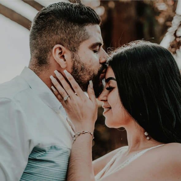 A man kissing a woman’s forehead