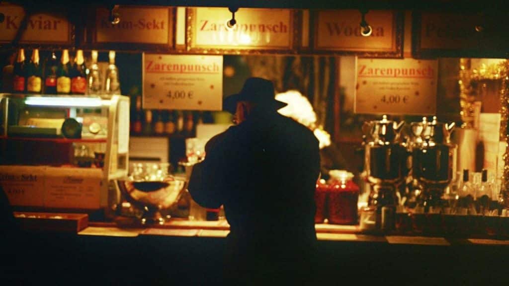 A person wearing a dark hat is seen from the back at a bar counter.