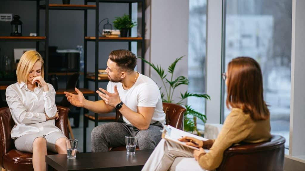 An unhappy couple is in a counseling session with a therapist.