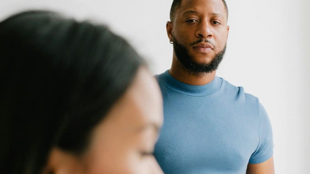 A bearded man in a blue shirt standing behind a woman with blurred hair.