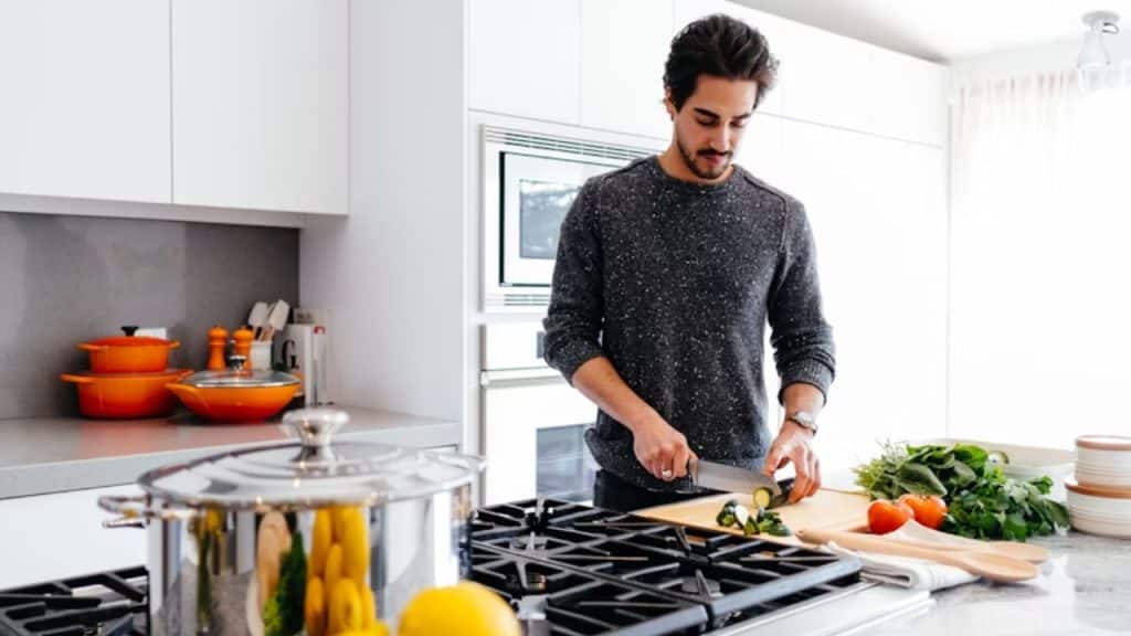 A man chopping vegetables while cooking dinner