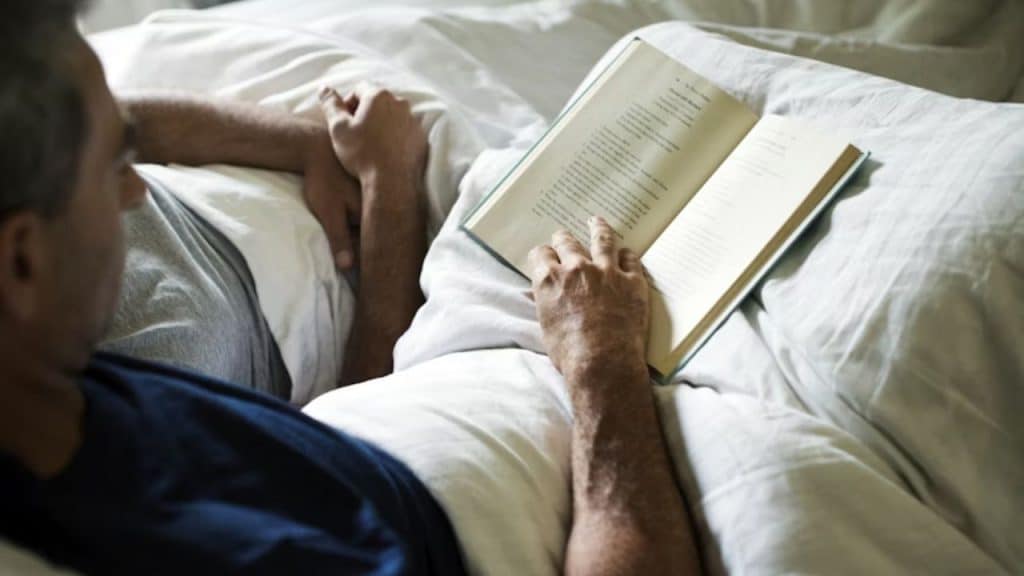 A man winding down with a book before bed