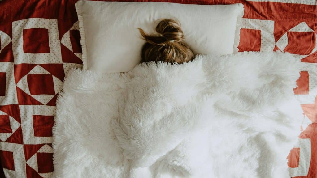 A man hiding under a plush blanket