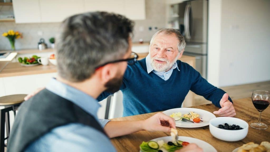 A man having a meal with his senior father