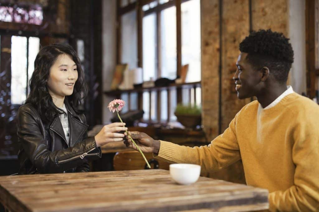 A man giving a flower to woman