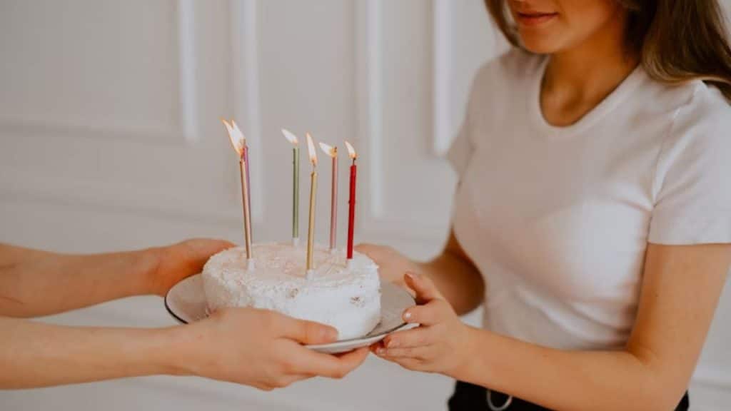A woman holding a cake with no visible joy while her husband looks on.