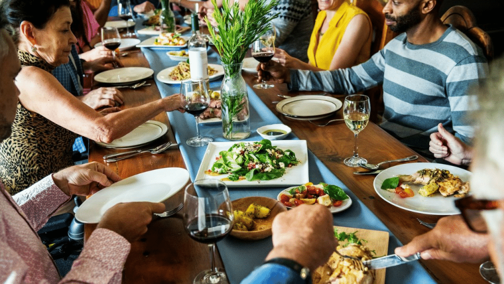A diverse group of people sits at a long table enjoying a shared meal.