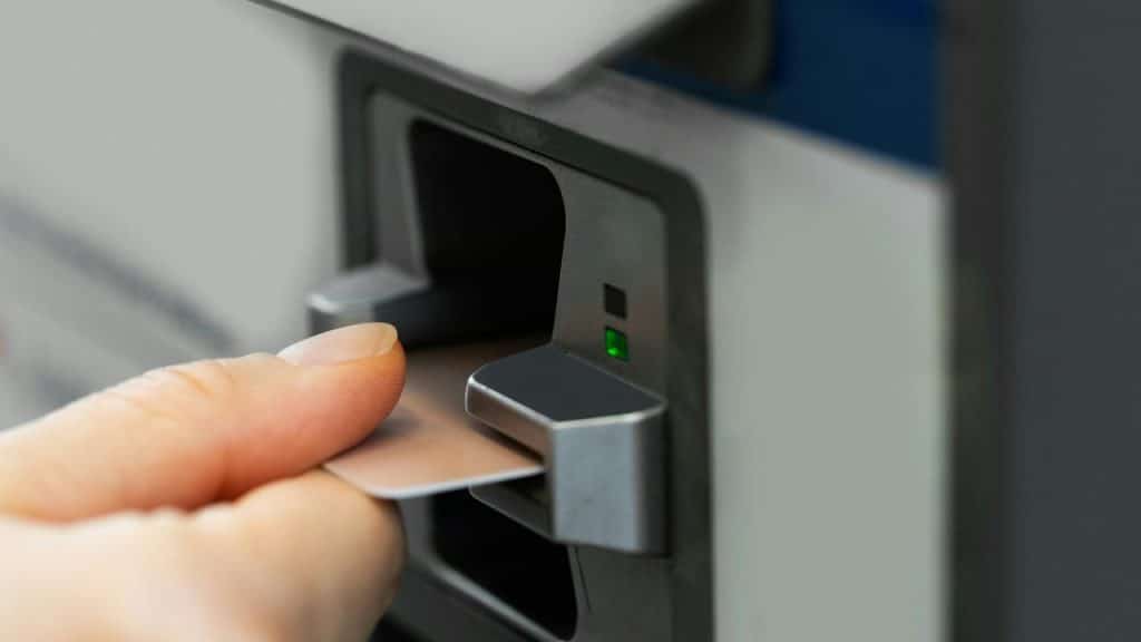 A person inserting a bank card into an ATM machine.