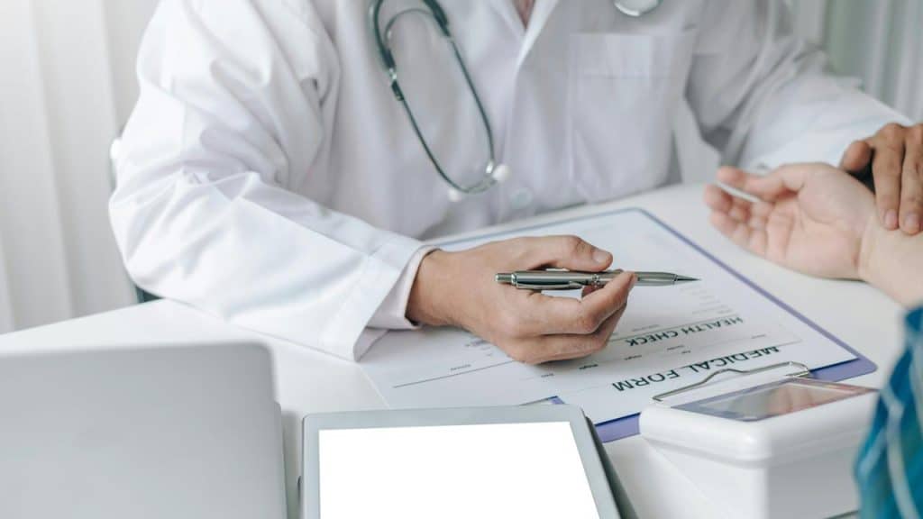 A doctor holding a patient’s wrist while reviewing a medical form.