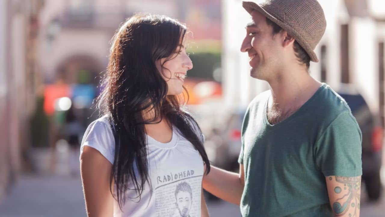 A man smiling at his partner as she explains something passionately.