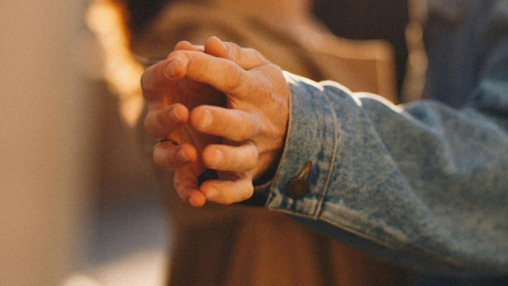 A couple holds hands closely in warm light.