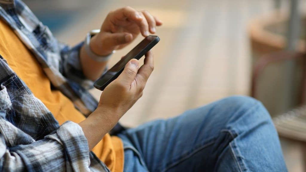 A person uses a smartphone while sitting outdoors.