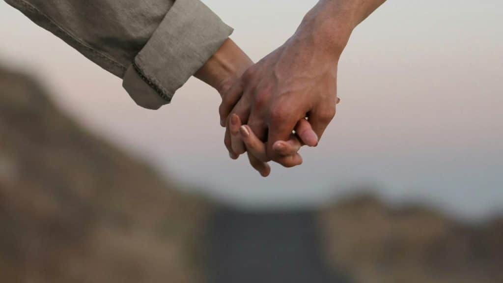 A couple holds hands while walking outdoors.