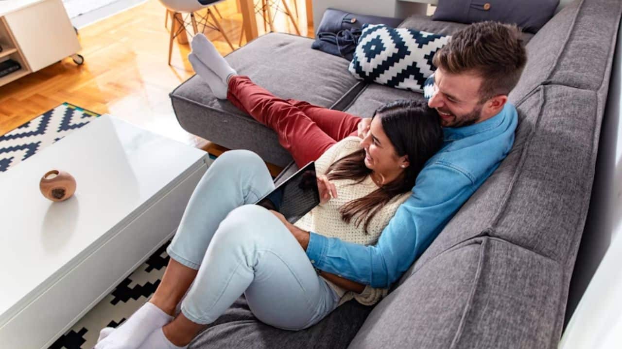 Couple cuddling on a couch watching TV.