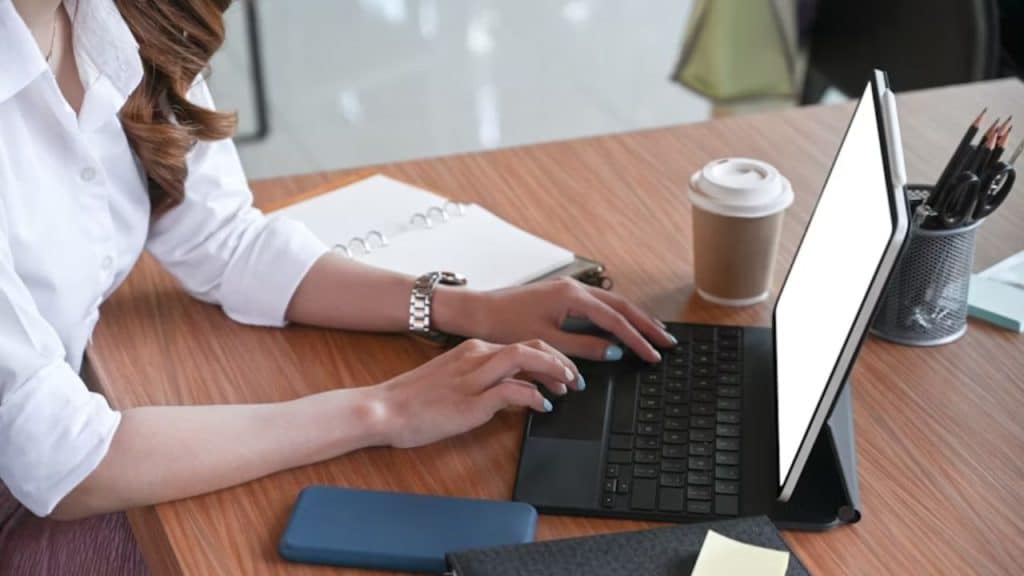 Woman reviewing finances on a laptop with coffee and documents on the table
