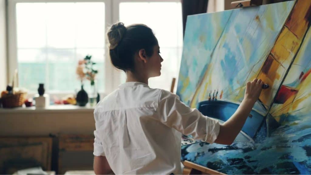 Woman painting on a canvas in a bright, modern studio
