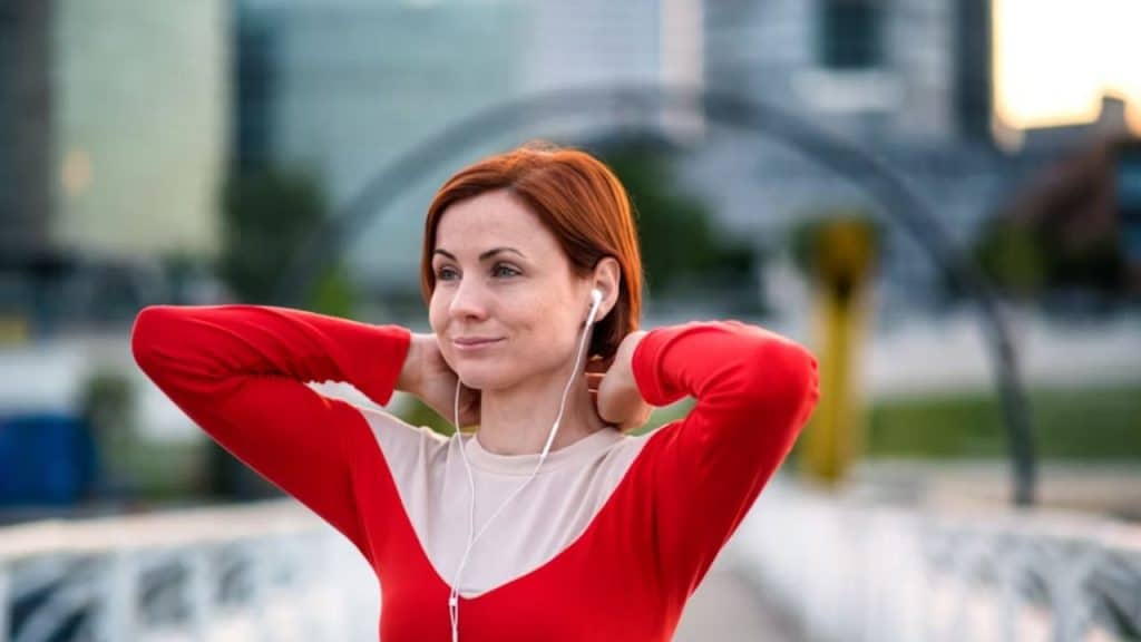 Woman smiling while walking outdoors with headphones in