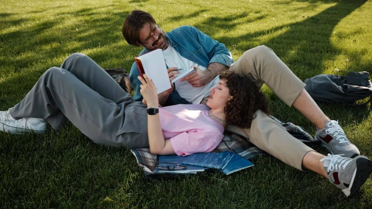 Man reading a book on self development while partner smiles proudly.