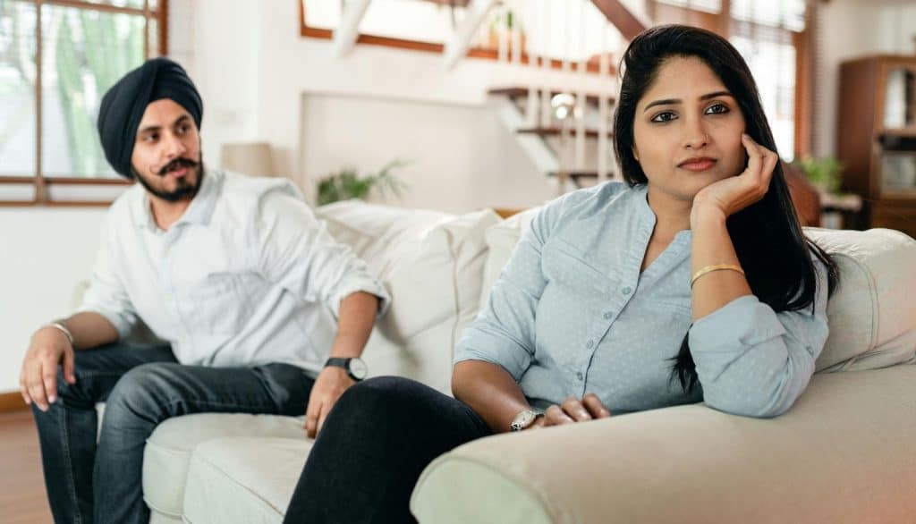A woman sulking and a man reaching her shoulder
