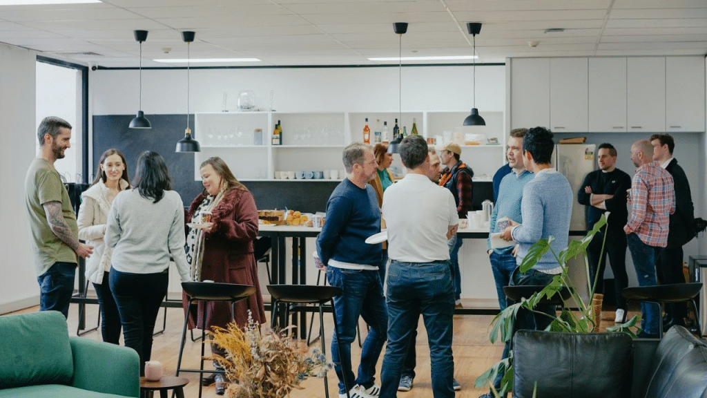 A large group of casually dressed people mingles at an office social event.