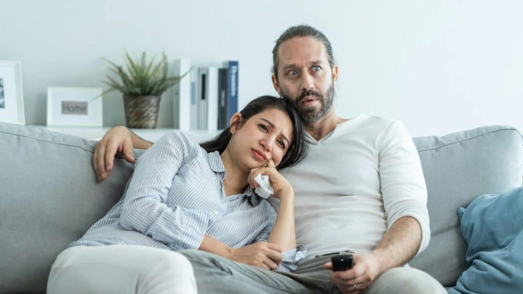 A sad woman leans on a man who seems comforting her.