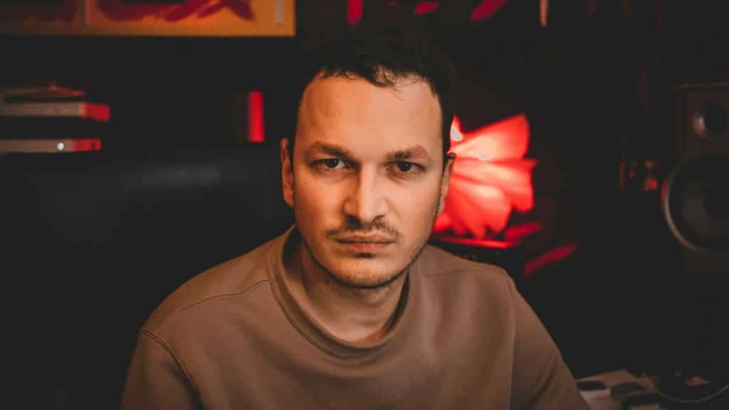 A man with short hair and a serious expression looks directly at the camera.