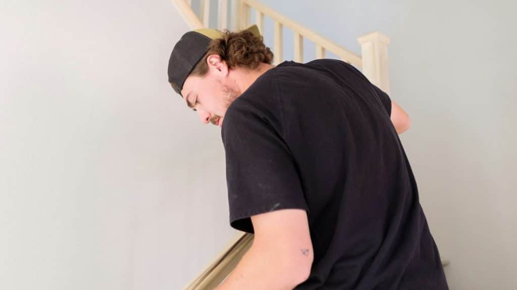A man wearing a black shirt and a backwards baseball cap is walking down a staircase.