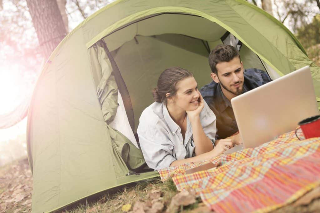 A woman watching a man using a laptop