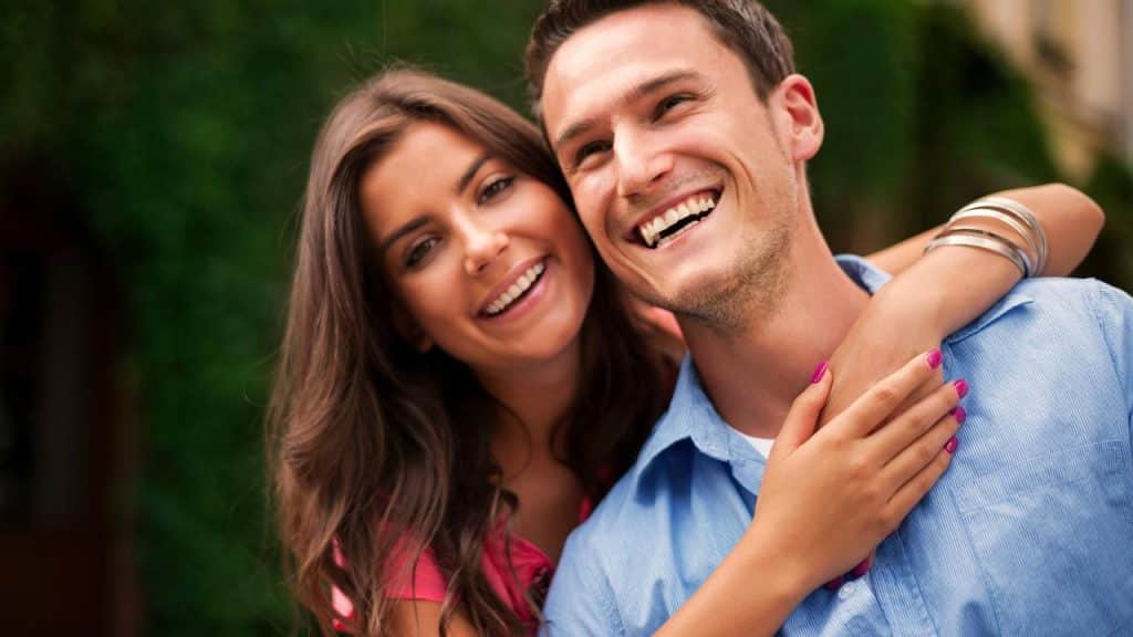 A happy couple smiling with arms wrapped around each other.