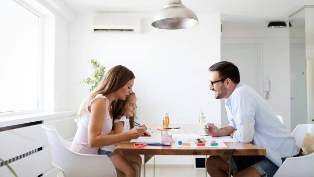 A family sitting at a table doing art activities together.