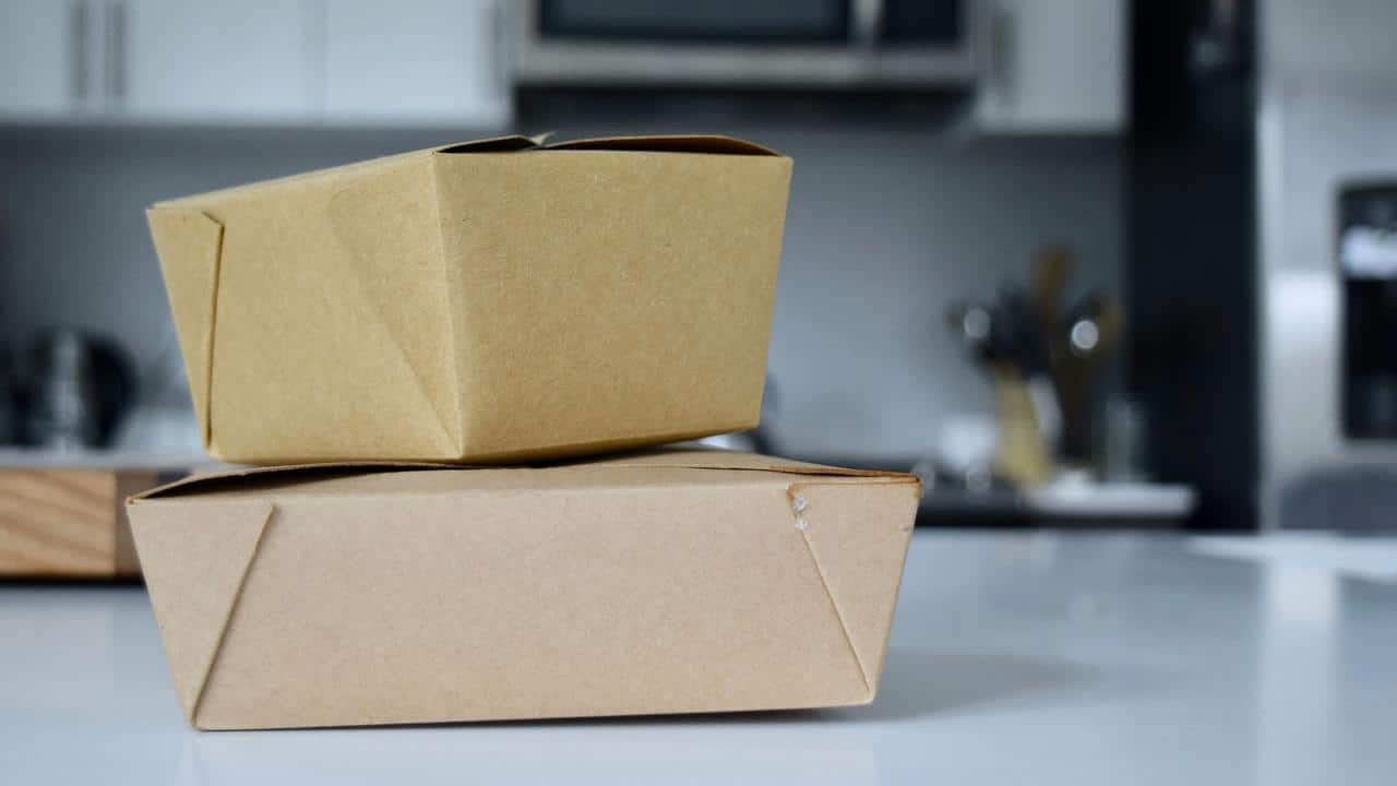 A pair of stacked brown takeout food containers on a counter.