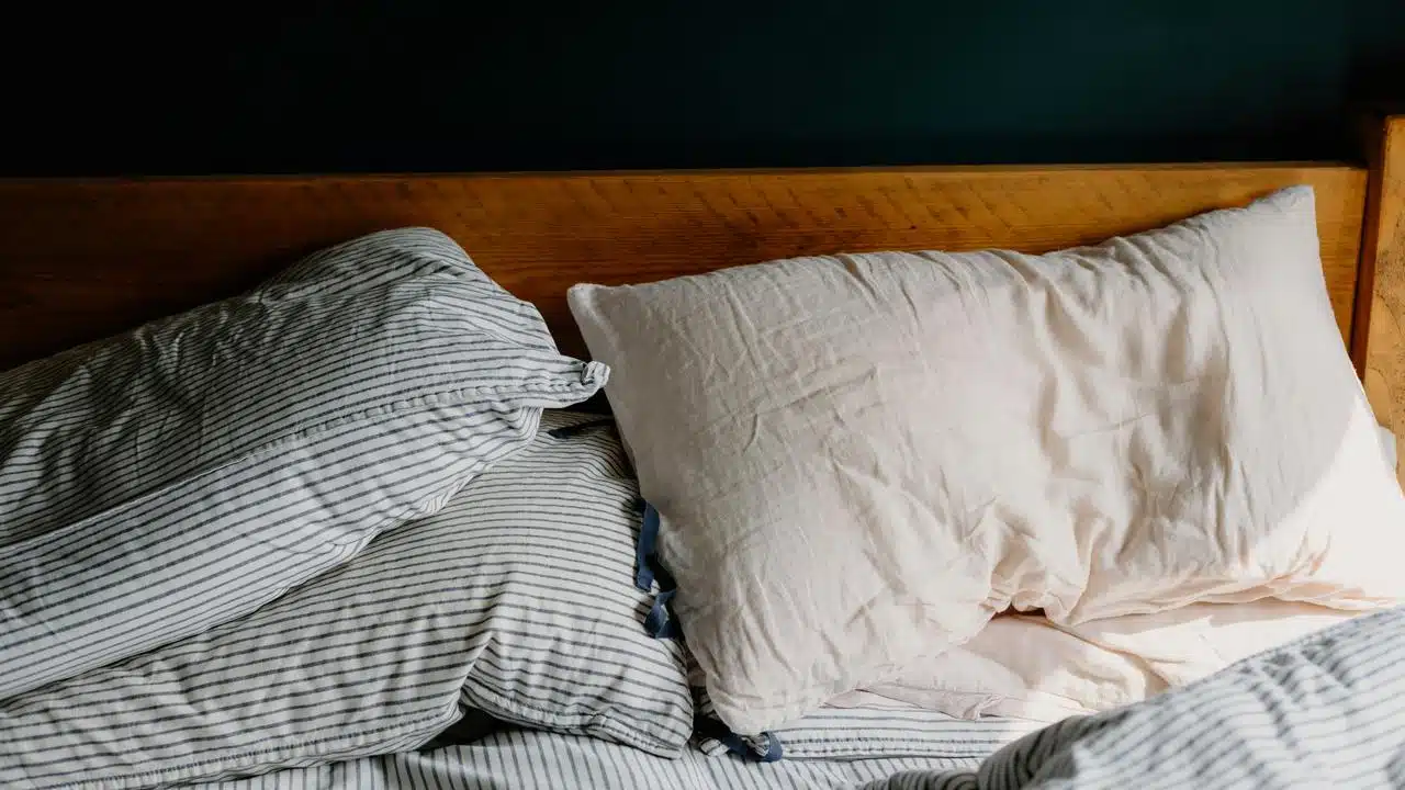A bed with striped sheets and pillows.