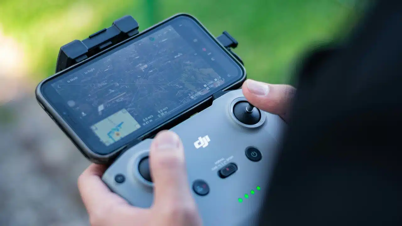 A person holding a drone controller with a phone screen display.