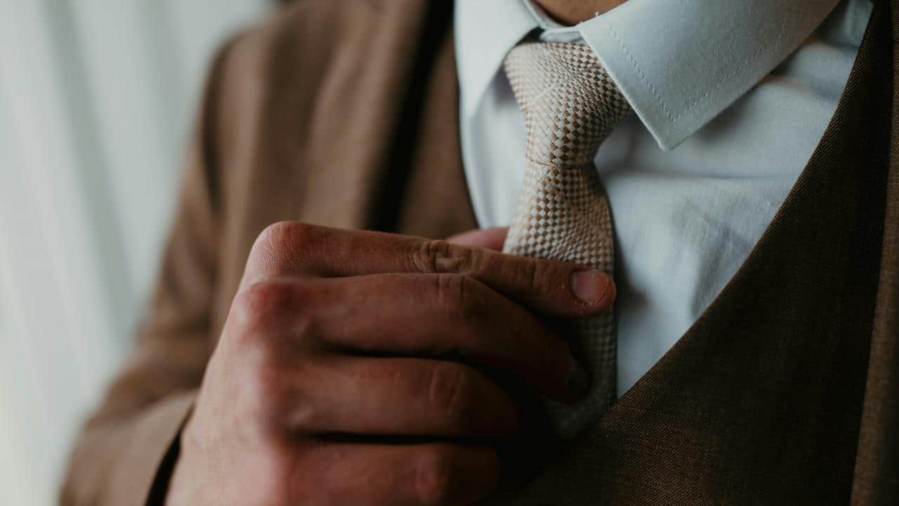A man adjusting his tie while wearing a suit.