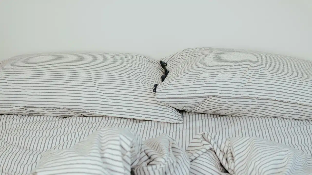 A neatly made bed with striped pillows and a matching blanket.