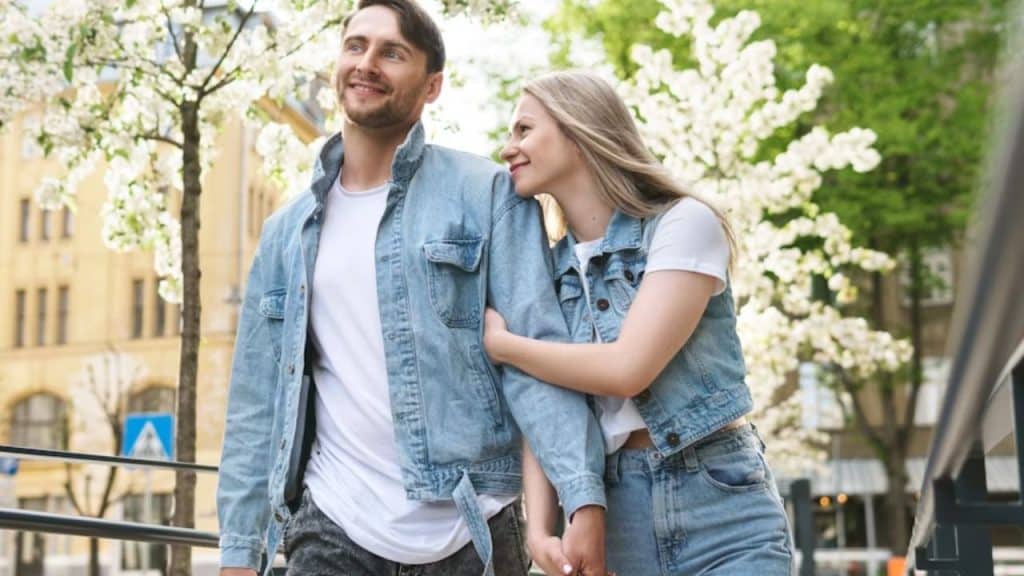 A couple smiling while holding hands on a city street